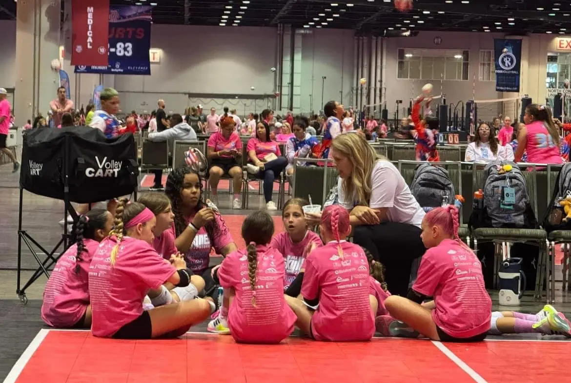 team-sitting-floor-pink Team sitting on floor with coach talking with them